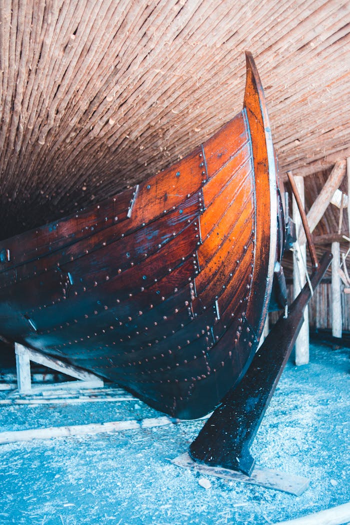 Close-up of a wooden boat stored indoors, showcasing its craftsmanship and detail.